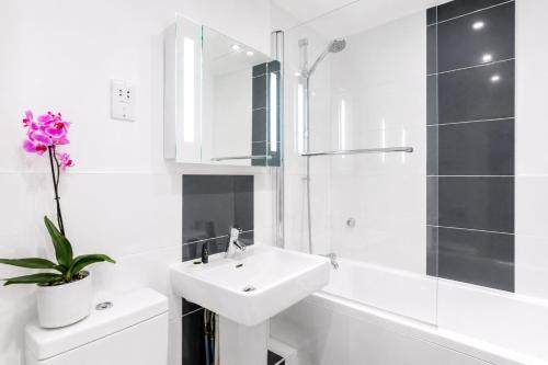 a white bathroom with a sink and a toilet and a shower at Roomspace Serviced Apartments - Capitol Square in Epsom