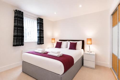 a bedroom with a large white bed with two lamps at Roomspace Serviced Apartments - Capitol Square in Epsom