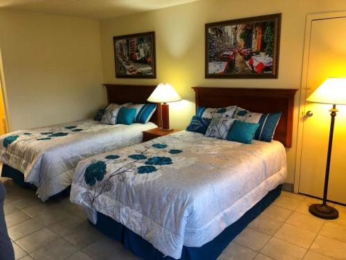 two beds in a hotel room with two lamps at Wolf Inn Hotel in Sandusky