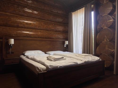 a bed in a room with wooden walls and a window at Villa ZRUB in Palyanytsya