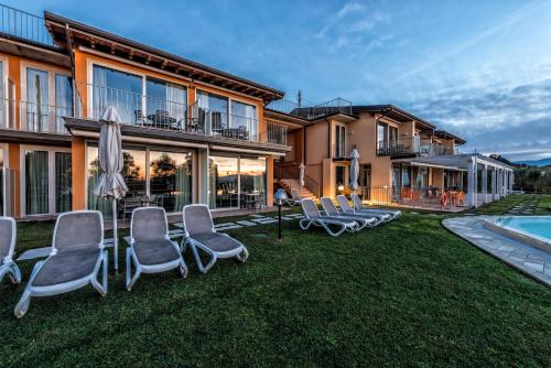 a group of chairs sitting on a lawn in front of a house at La Chioma di Berenice Garda Residence in Toscolano Maderno