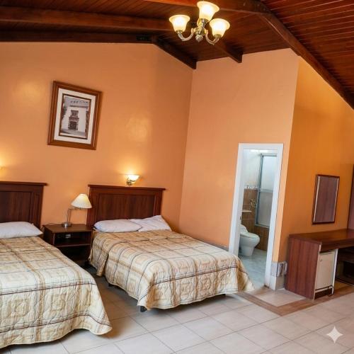 a bedroom with two beds and a bathroom at Hosteria Quinta Aidita in Guano