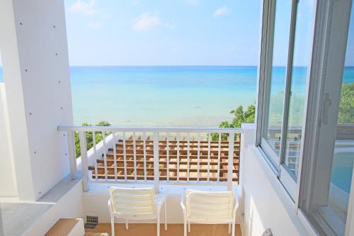 a balcony with two chairs and a view of the ocean at Seven Colors Ishigakijima in Ishigaki Island