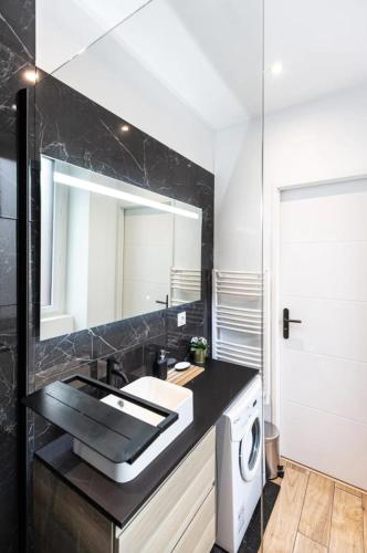 a bathroom with a sink and a mirror at Le Vivaldi - Studio Hypercentre Saint-Étienne in Saint-Étienne