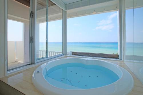 a bath tub in a room with a view of the ocean at Seven Colors Ishigakijima in Ishigaki Island