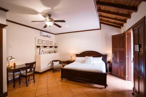 a bedroom with a bed and a desk and a ceiling fan at Hotel Plaza Colon - Granada Nicaragua in Granada