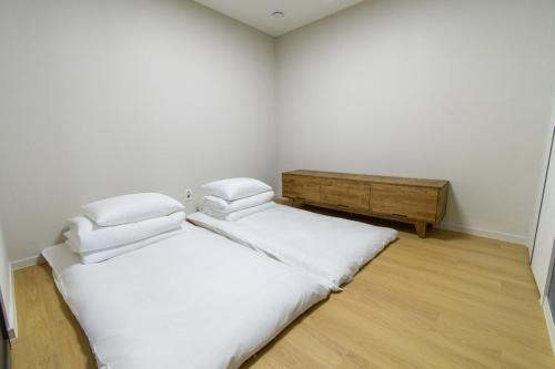 two beds in a room with white walls and wooden floors at 플럼바고올스위트1107 in Chosan-ni