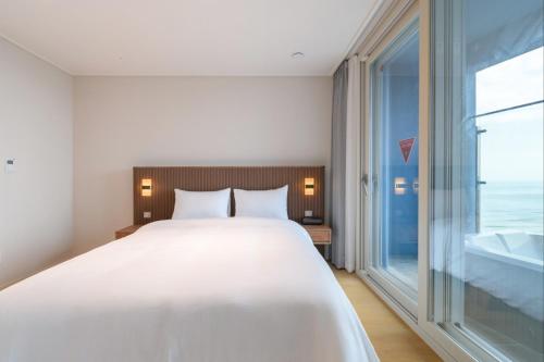 a bedroom with a large bed and a large window at 플럼바고올스위트1107 in Chosan-ni