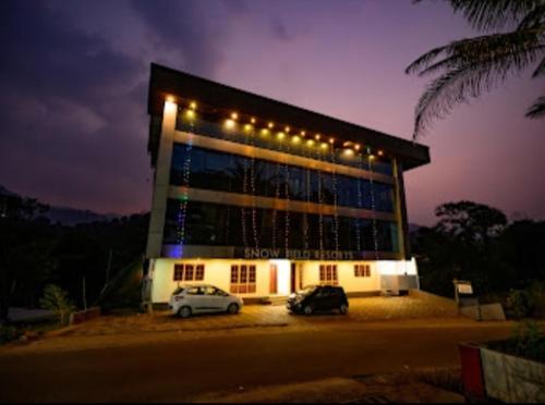 two cars parked in front of a building at night at Skybz Resort - Mankulam in Viripara