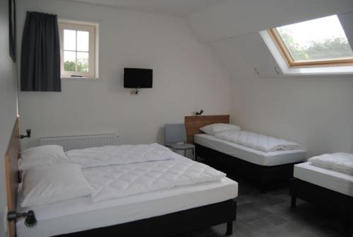 a bedroom with two beds and a tv on the wall at Duinoord Oostkapelle in Oostkapelle