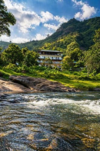 a river with a building on the side of a mountain at Skybz Resort - Mankulam in Viripara