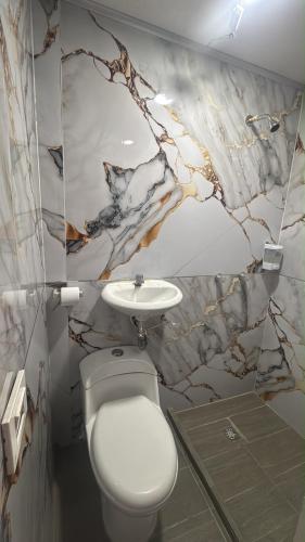 a bathroom with a white toilet and a sink at Hotel sahara in Medellín