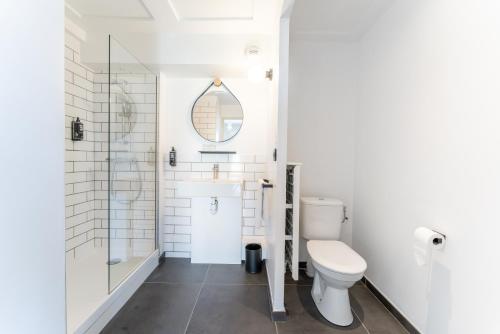 a white bathroom with a toilet and a mirror at Ibis Centre Millau in Millau