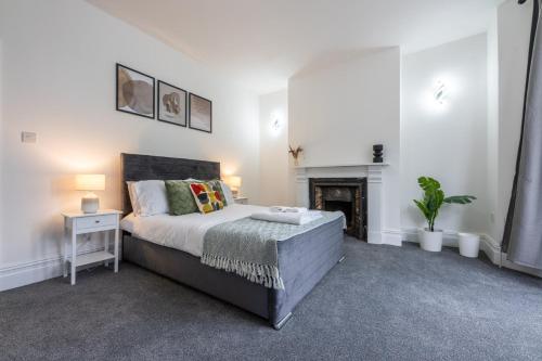 a white bedroom with a bed and a fireplace at Spacious 6BR Cardiff House w/ Free Parking in Cardiff