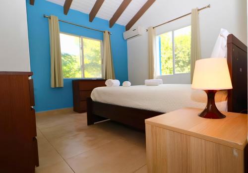 a bedroom with blue walls and a bed with a lamp at Blue Sail Apartments in Simpson Bay