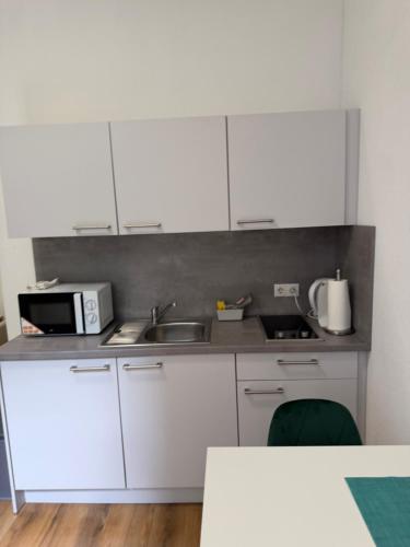 a kitchen with white cabinets and a sink and a microwave at Felix Appartment H1a in Koblenz