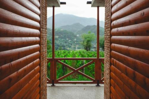 an open door to a balcony with a view of a garden at Jvarisa cottages in Bugeuli