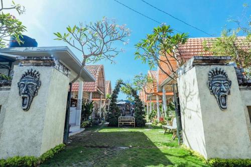 two stone walls with masks on them in a yard at The Box Paradise Bungalow in Nusa Penida