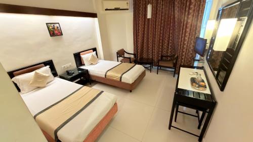 a hotel room with two beds and a table at Hotel Garden Panvel - Near Navi Mumbai Airport in Navi Mumbai