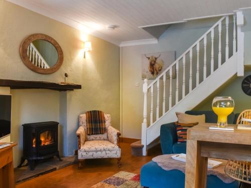 a living room with a fireplace and a staircase at Granary Cottage in Kirkby Malham