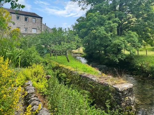 a river in front of a building next to a building at Granary Cottage in Kirkby Malham