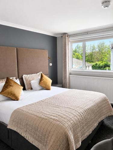 a bedroom with a large bed with a window at The Popinjay Hotel in Larkhall