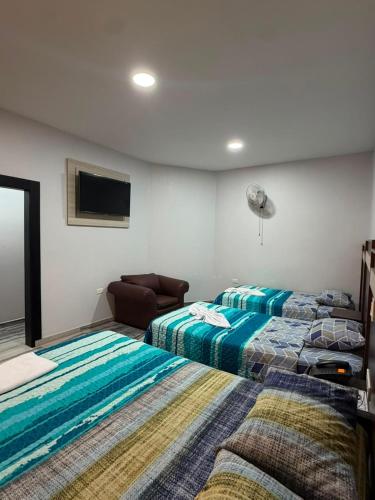 a bedroom with two beds and a flat screen tv at Hotel Imperial in Santo Domingo de los Colorados
