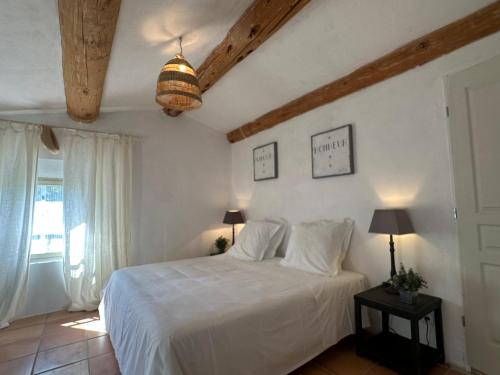 a bedroom with a white bed and a window at Perseïdes in Saignon