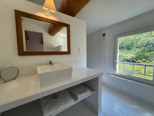 a bathroom with a sink and a mirror and a window at Perseïdes in Saignon