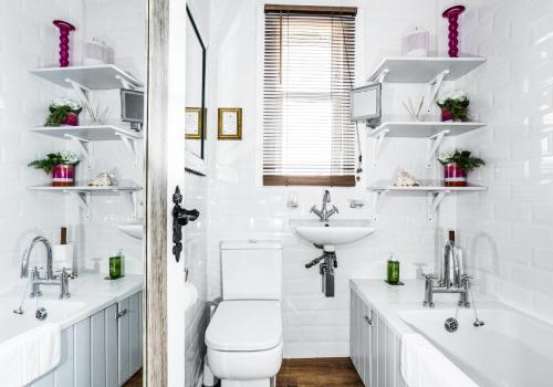 a white bathroom with two sinks and a toilet at Lynn Cottage in East Linton