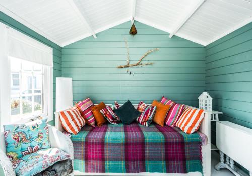 a blue room with a bed with colorful pillows at Lynn Cottage in East Linton