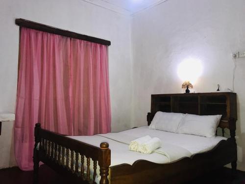 a bedroom with a large bed with a pink curtain at Sapphire Homestay in Palle Deltota