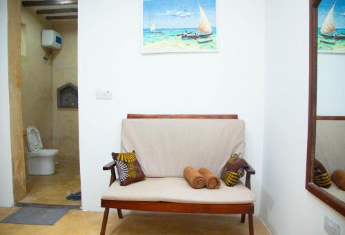a chair with pillows and a painting of a sailboat at Boha Zanzibar Beach House in Bwejuu