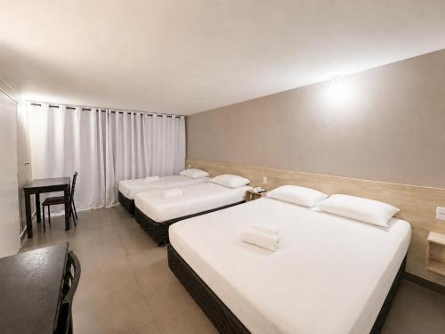 a hotel room with two beds and a desk at Hotel Montana Aeroporto by Bsb Inn in Brasília