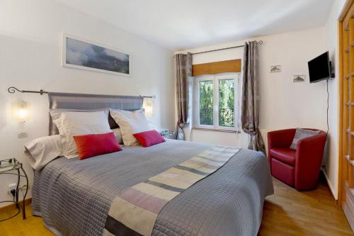 a bedroom with a bed and a red chair at La Prairie de Vassy in Vassy