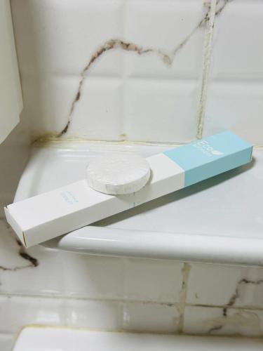 a white toilet with a book on a shelf at mudha hotel in Hargeysa