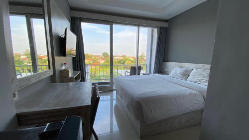 a bedroom with a bed and a desk with a window at Shashvata Berawa in Badung