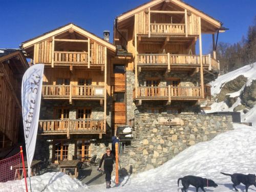 a woman walking in the snow in front of a building at Black Diamond Sainte Foy Chalets in Sainte-Foy-Tarentaise