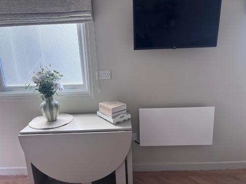 a white room with a vase of flowers on a table at Riverhill in Abersoch