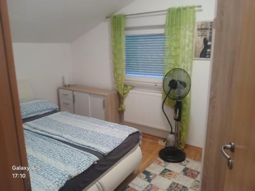 a bedroom with a bed and a window with a fan at Apartments Tutto Bene in Jajce