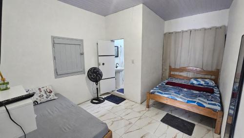 a small bedroom with a bed and a refrigerator at Casa Vigia 1 Quarto in Vigia