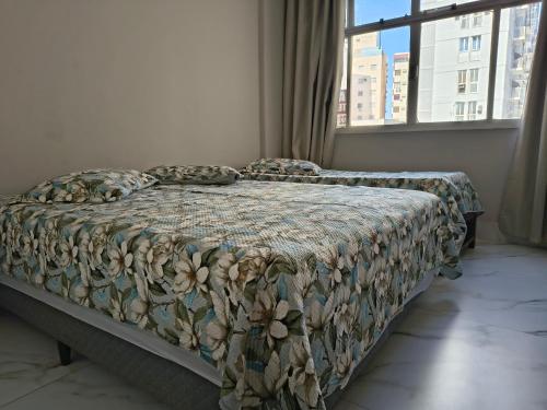 a bed with a comforter and pillows in a bedroom at Castanheiras,perto de tudo,Internet,cadeiras,cooler e guarda sol in Guarapari
