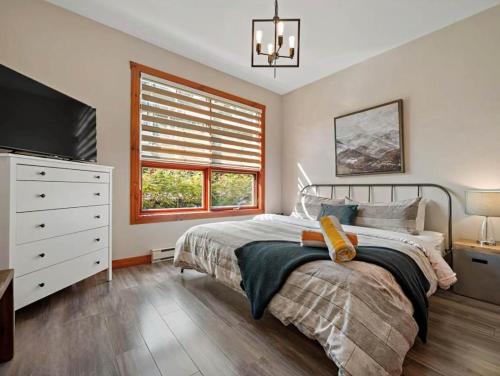 a bedroom with a bed and a dresser and a window at Tremblant Les Eaux by Rendez-Vous Mont-Tremblant in Mont-Tremblant