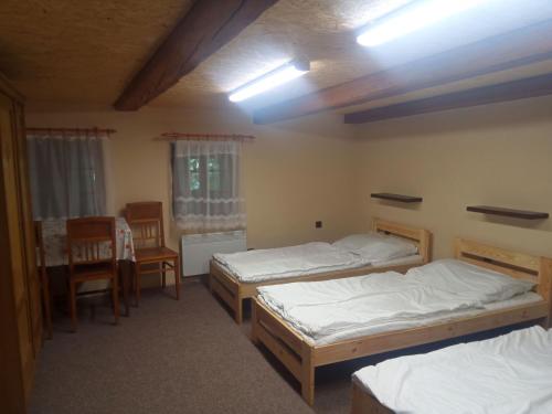 a room with three beds and a table and chairs at Chalupa U Tety v Bystrém in Dobruška