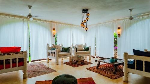 a living room with white curtains and chairs and a table at Villa Amani in Malindi