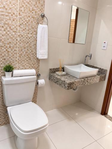 a bathroom with a white toilet and a sink at Hotel Vista Bela in Itamaraju