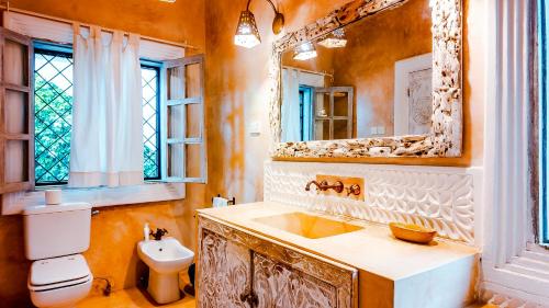 a bathroom with a sink and a toilet and a mirror at Villa Amani in Malindi