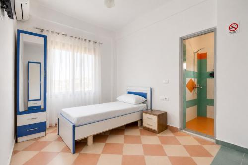 a small bedroom with a bed and a mirror at South Hotel Berat in Uznovë