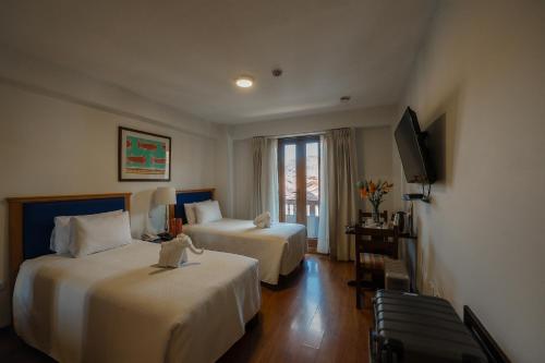 a hotel room with two beds and a television at San Agustin El Dorado in Cusco