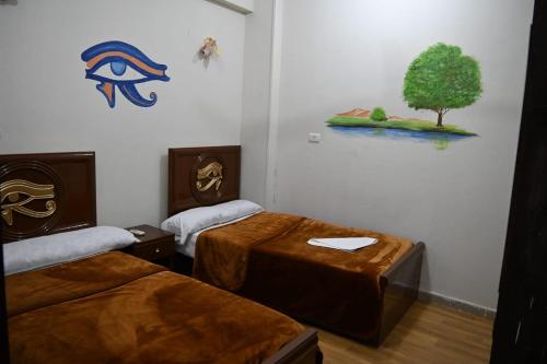 a room with two beds and a tree on the wall at شقة رويال سويت in Abu Simbel